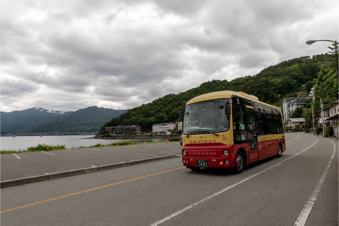 Fuji Kyuko bus driving along Lake Kawaguchiko with mountain views during a Mt. Fuji Tours experience with our agency